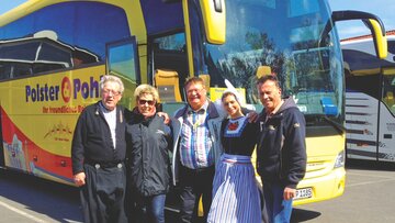 Zufriedene Reiseteilnehmer vor dem Bus